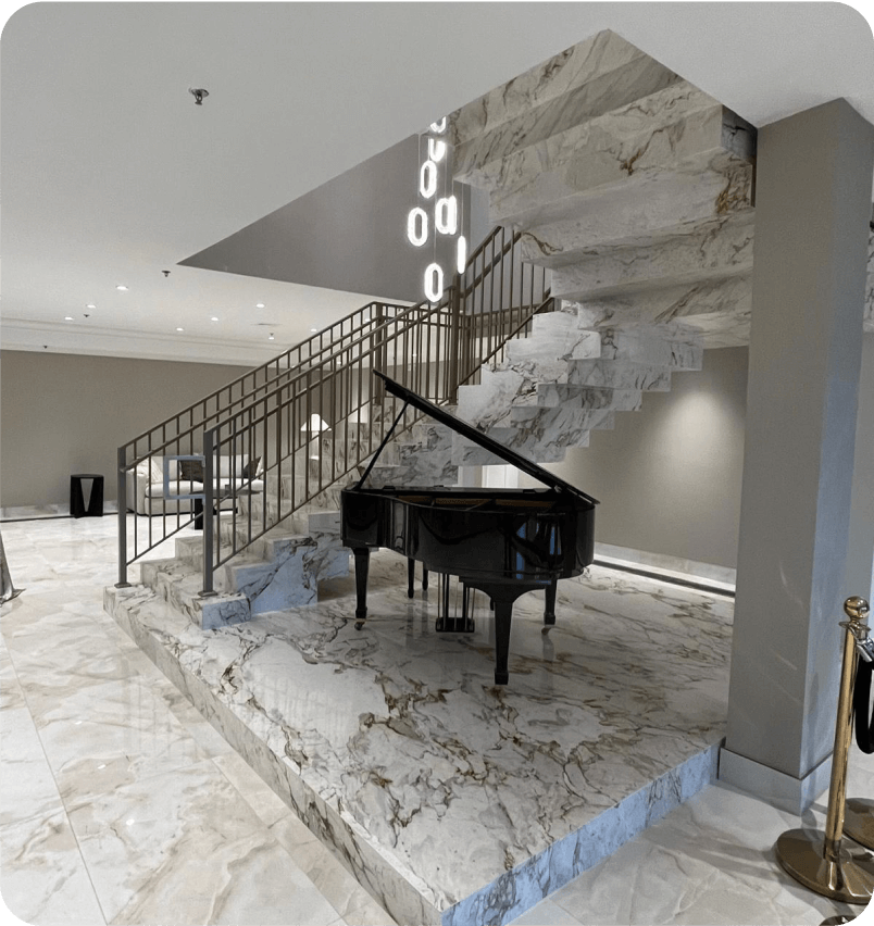 A grand piano at the foot of the marble staircase