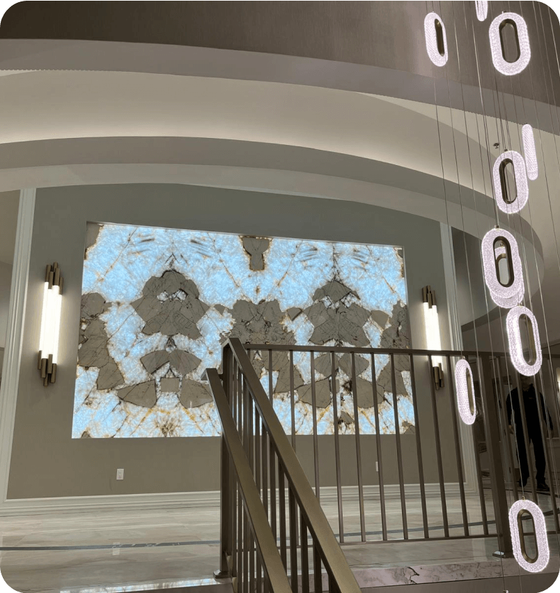 The lobby staircase with backlit stone wall and pendant lights