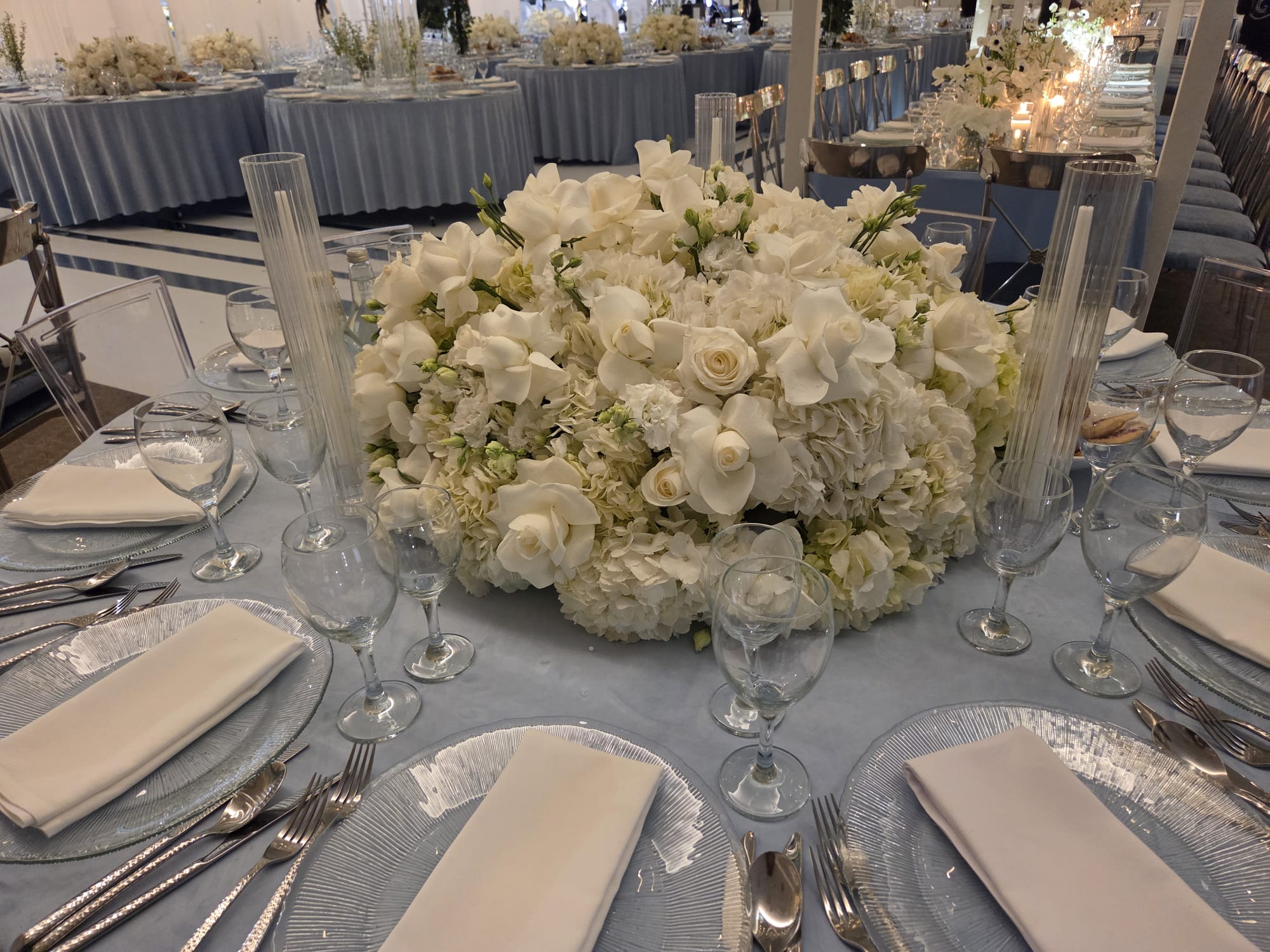 A low centerpiece of white roses on a set table