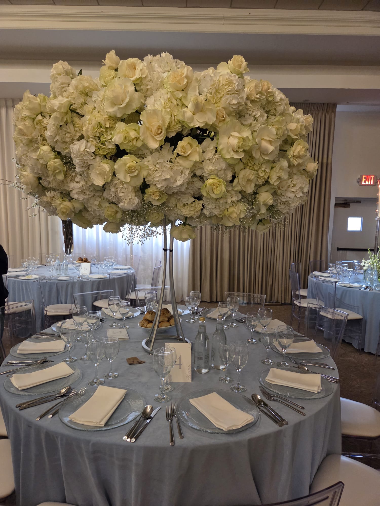 A tall arrangement of white roses above a set table