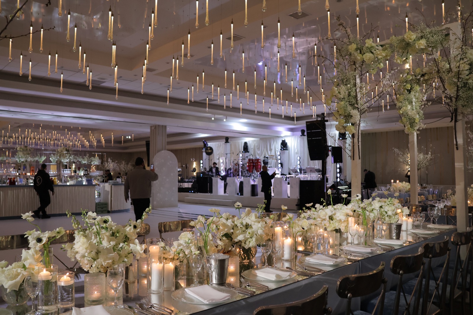 A long candlelit table under the ballroom lights