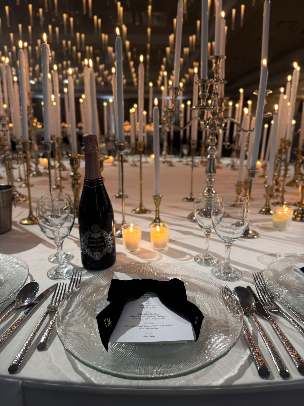A place setting with tapered candles and a printed menu